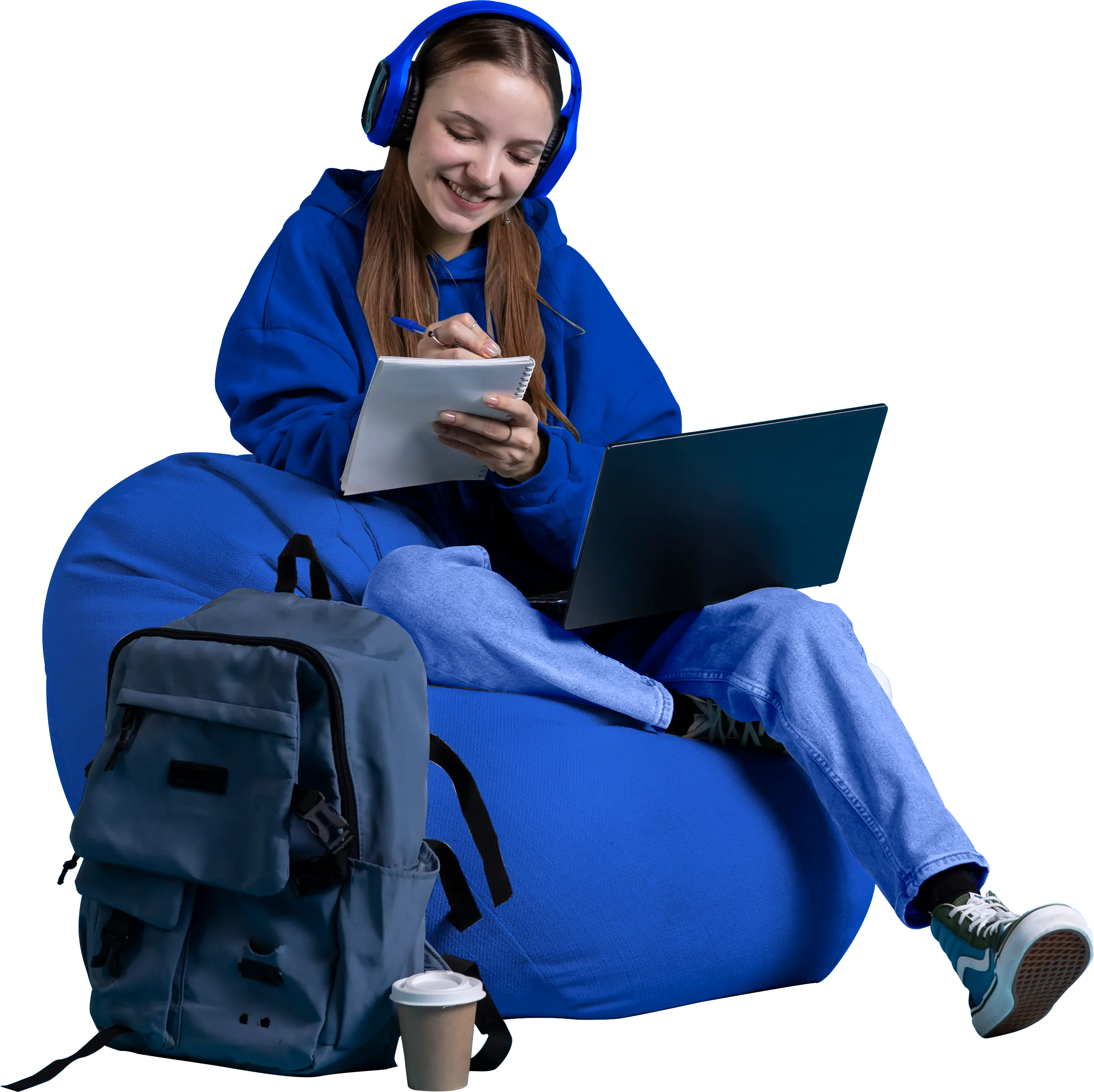 Student with headphones taking notes on a beanbag with a laptop